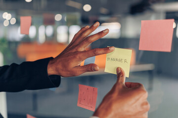 Businesswoman hand's is sticking sticky notes on business board in office