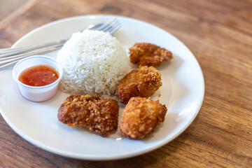 The dish of deep fried croquette and white jasmine rice and red dipping sauce with fork and spoon. 