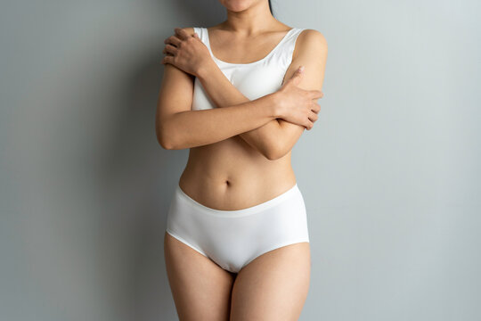 Cropped image of sexy attractive young woman in white underwear showing fit body standing posing hold hand on hips legs isolated on white wall background studio portrait