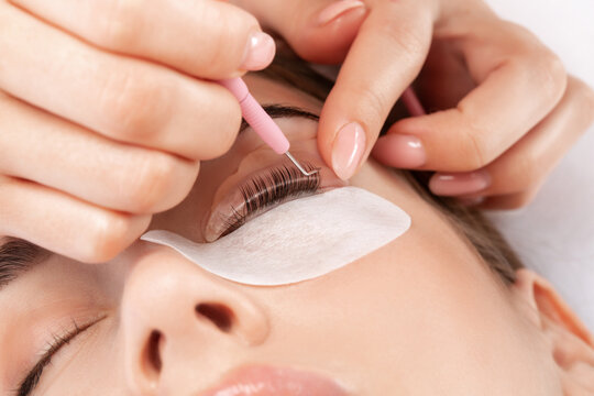 Make-up artist makes the procedure of lamination and dyeing of eyelashes to a beautiful woman in a beauty salon. Eyelash extensions. Eyelashes close-up - Powered by Adobe