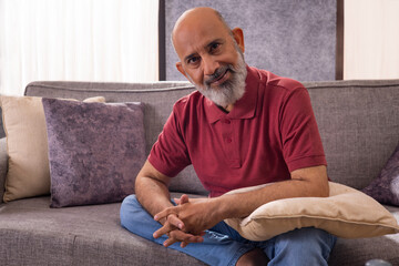 Portrait of senior man sitting on sofa and looking at camera