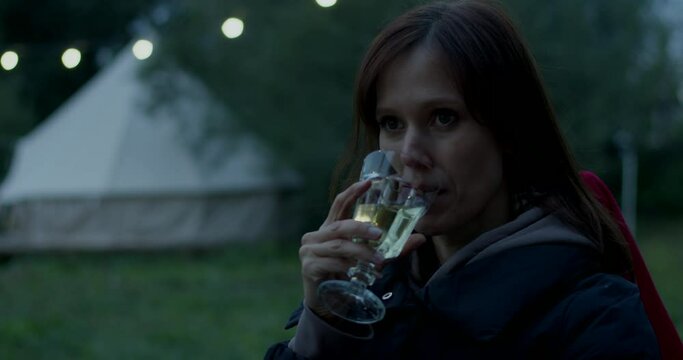 Portrait woman on vacation relaxing with glass of wine in camsite in evening. Medium shot