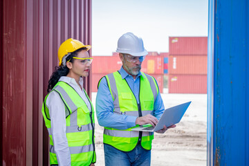 Engineer working in the construction container dock yard checking and inspection containers data on laptop program is container shipping Logistics business concept.