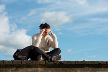 Woman sitting outside with her head in her hand, looking upset or down. © Rob Wilkinson