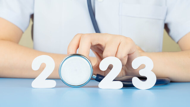 Happy New Year For Health Care And Medical Concept. Doctor In White Uniform Holding Stethoscope With Number 2023 On Doctor Desk. Idea For New Trend In Medicine Treatment And Diagnosis.