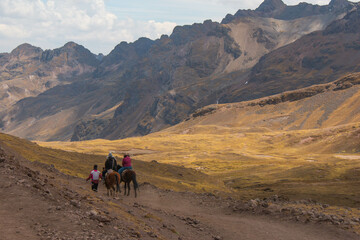 Horseback riding in the Rainbow Mountain in Peru. Couple riding horse with companion and view of the mountains. 
