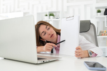 Young attractive female doctor consulting her patients online in the office