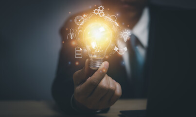 Close-up of businessman holding a bright light bulb, business idea concept, creativity ,Inspire to...