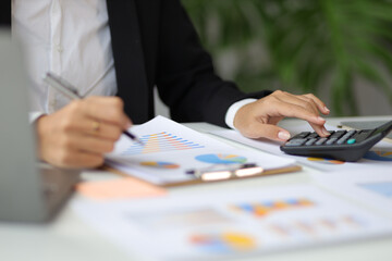 Financial planning and accounting. Accountant in an accounting firm working with financial audits and budgeting using a calculator and laptop.