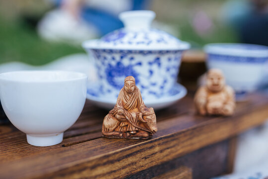  Buddha statue for Chinese tea ceremony on wood table. Ceramic gaiwan and tea cups close-up. 