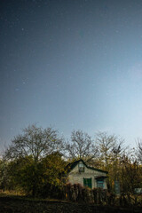 house at  forest in the night . Night landscape. Nightsky and clouds . Stars in the sky . Lights of the city . 