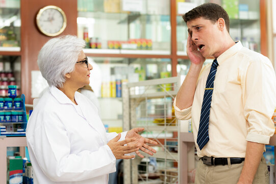 A young caucasian man consults a pharmacist about his illness.