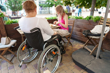 Woman wheelchair user dining at a restaurant with her young daughter.