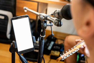 Singer reading song lyrics on smartphone screen which hold on phone holder for microphone stand. Music performer mic gadget during rehearsal performance in recording studio.