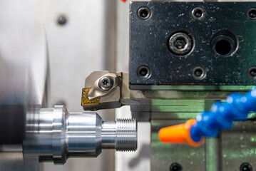 The CNC lathe machine thread cutting at the end of metal stud parts.