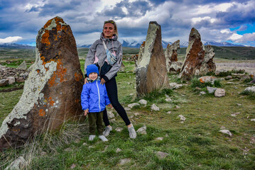 The girl with a small child near a megalithic standing stone, Zorats karer or Karahunj is a...