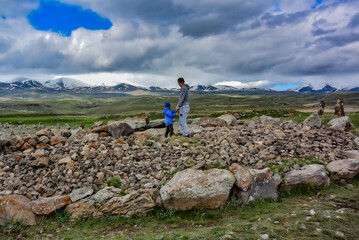 A man with a child near a megalithic standing stone, Zorats karer or Karaunj is a prehistoric...