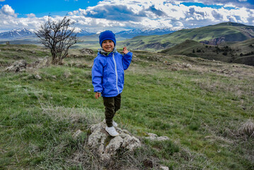 A little boy near a megalithic standing stone, Zorats karer or Karahunj is a prehistoric monument in Armenia. May 5, 2019.