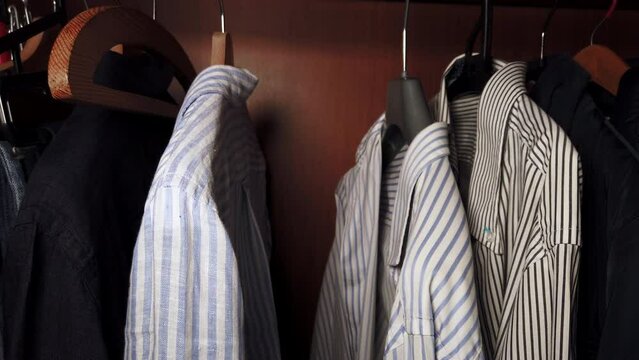 A man takes a shirt out of his wardrobe