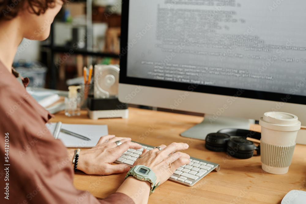Poster Hands of young female programmer typing on computer keyboard while decoding data on computer screen by workplace in office