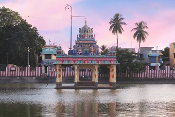 An image of a South Indian temple in a pond with water in the background was taken in the evening