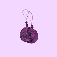 Purple Christmas tree ball with shadow isolated on a light purple background.
