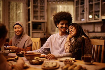 Happy Muslim couple enjoying in dinner with their family at dining table.
