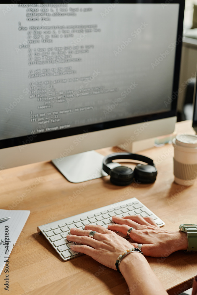 Poster Young businesswoman or programmer pressing keys of computer keyboard while sitting by desk in front of monitor and decoding data