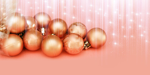 pile of Christmas decoration pink balls over pink background with copy space, stars and rays of...