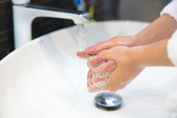 Woman washing hands in the modern bathroom at home
