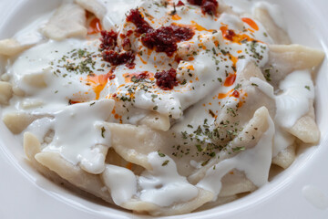 Turkish traditional food ravioli with yoghurt and tomato sauce in plate, manti