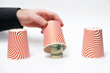 Money fraud. Close up of male hand opens paper cup, showing rolled-up dollars. White background....