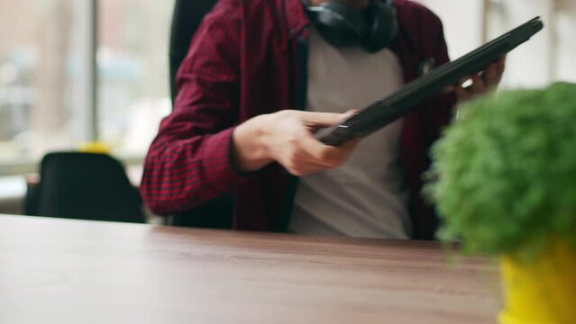 Tired office worker finishes work, takes a break, closes laptop. Overworked developer ends working day in coworking, goes home. Freelancer ends project, leaves workplace with computer for lunch.
