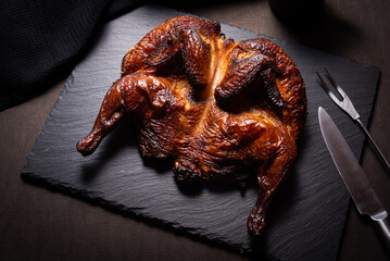 Traditional skoked full chicken on black stone plate © mdbildes