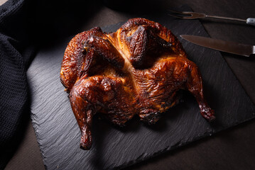 Traditional skoked full chicken on black stone plate © mdbildes
