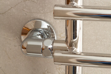 Modern new heated towel rail on a marble wall close-up