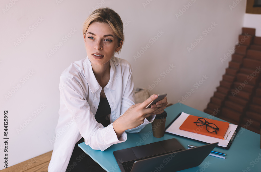 Aufkleber contemplative female blogger with modern cellphone device thoughtful looking away while creating con
