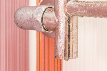 Wet heated towel rail covered with condensate. Close-up