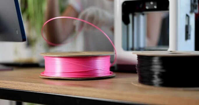 Engineer in gloves holds pink plastic for 3d printers