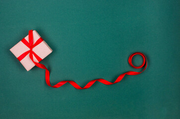 Christmas wrapping background with gift box in craft paper, tied long red ribbon
