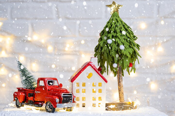 Christmas decor red retro car pickup truck on snow with fairy lights in bokeh Christmas tree. New...