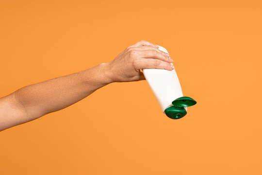 concept of running out of shampoo. white bottle with an open lid upside down in hand