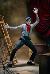 Vintage portrait of male mime artist expressing sadness and loneliness over dark retro circus...