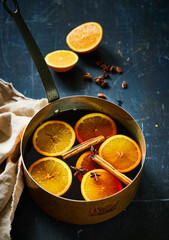 Mulled wine in a copper pan with slices of orange and cinnamon sticks