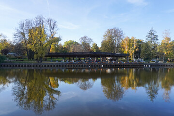 Fototapeta na wymiar Pavilion for rest on the lake and reflection on the water in autumn public park