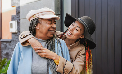 Happy african mother and adult daughter having tender moment in the city during vacation
