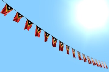 pretty memorial day flag 3d illustration. - many Timor-Leste flags or banners hanging diagonal on rope on blue sky background with selective focus
