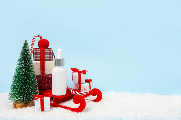 Cosmetic oil product, moisturizing facial serum in a white dropper on a christmas blue background.