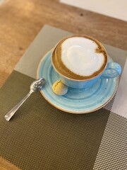Fresh amazing hot cappuccino in blue cup. Traditional breakfast coffee. Beautiful appetites cafe background. Drink view.
