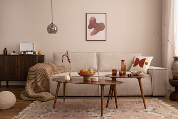 Domestic and cozy interior of living room with mock up poster frame, modern beige sofa, coffee...